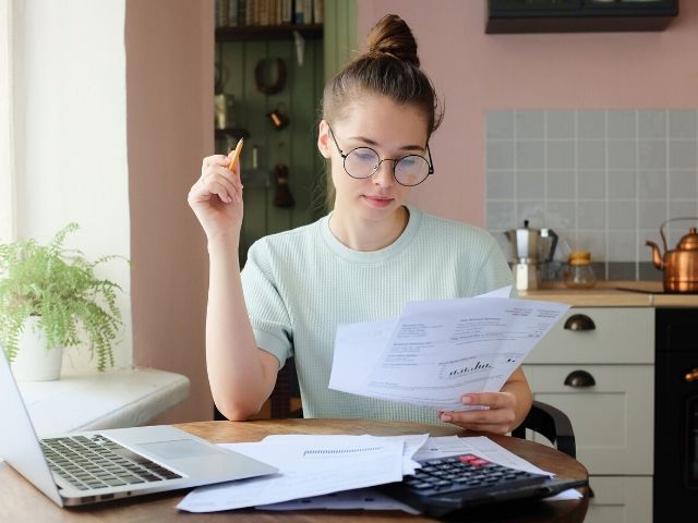 Woman looking through paperwork to see if she gets a penalty for not having health insurance coverage related to IRS form 8965.