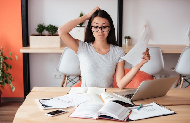A woman with glasses scratching her head stumped by paperwork on is homeschooling tax deductible