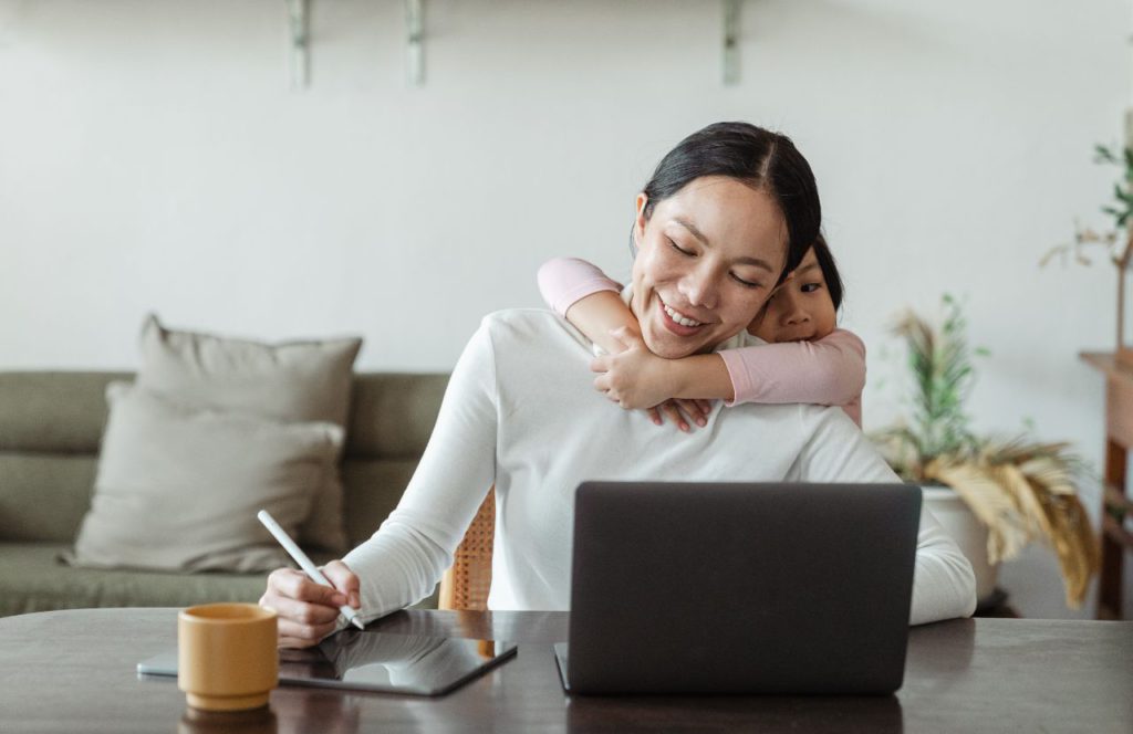 woman freelancer and get a hug from her child as she calculate her mileage reimbursements