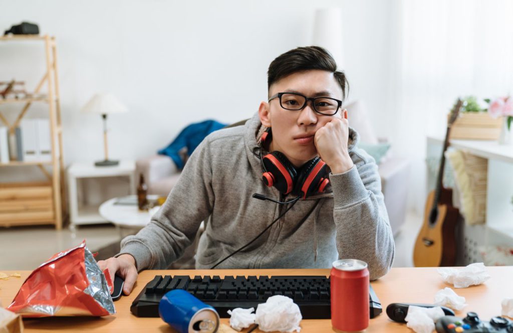 man setting at their desk full of junk food clicking on a mouse worried about their tax problem