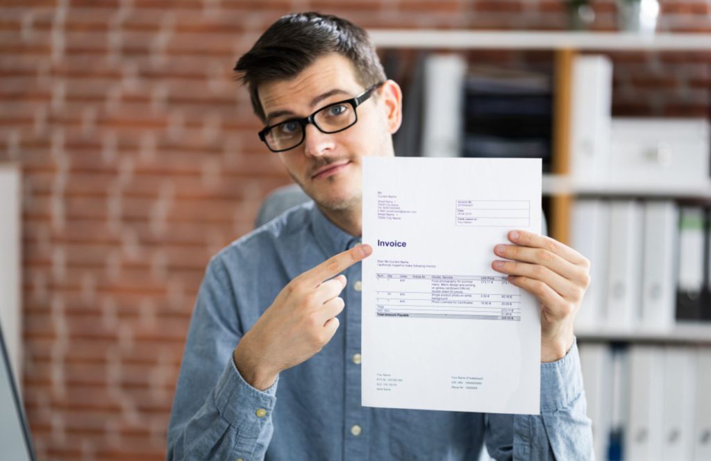 man with glasses holding and pointing at an invoice structured settlement and taxation.