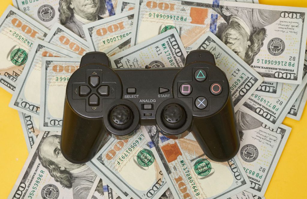 playstation controller on top of 100 dollar bills