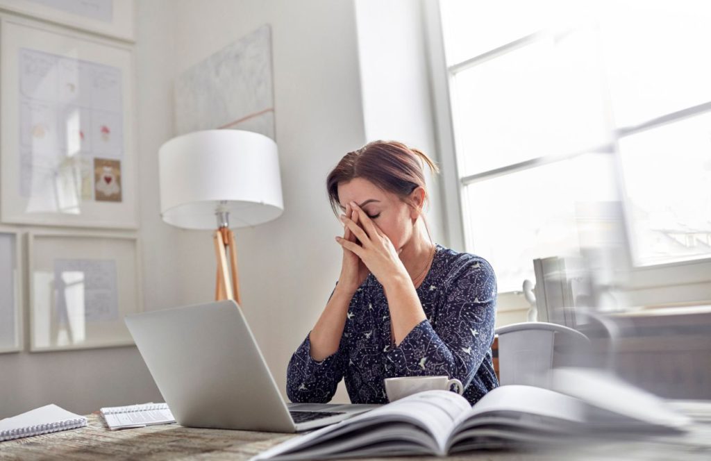 woman frustrated looking at computer and documents and needing tax resolution.