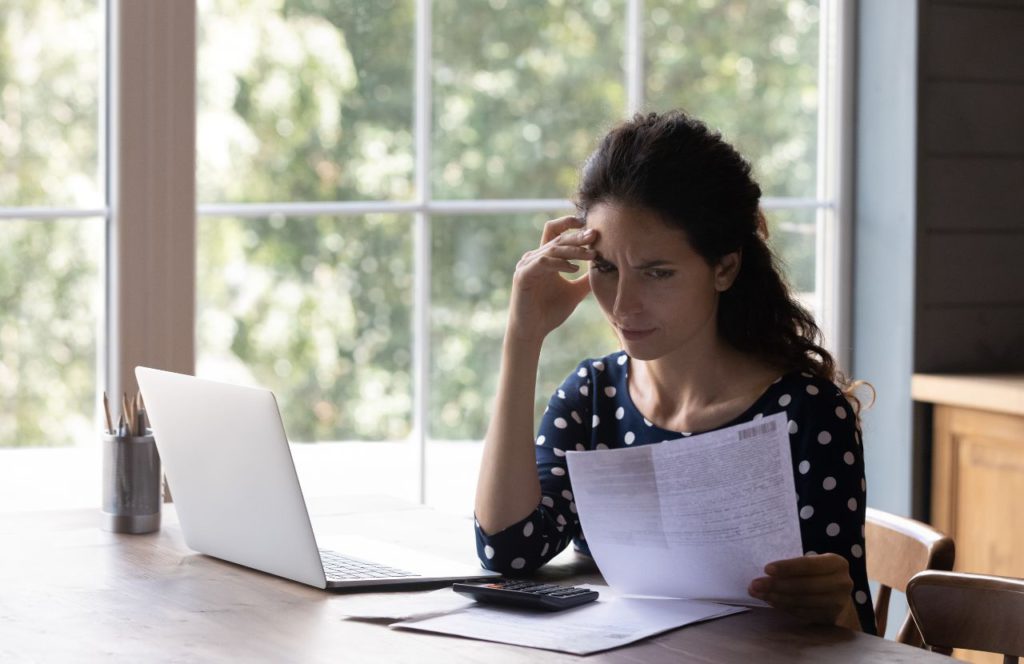 woman looking over a document at her desk looking confused on the difference between tax evasion vs tax fraud