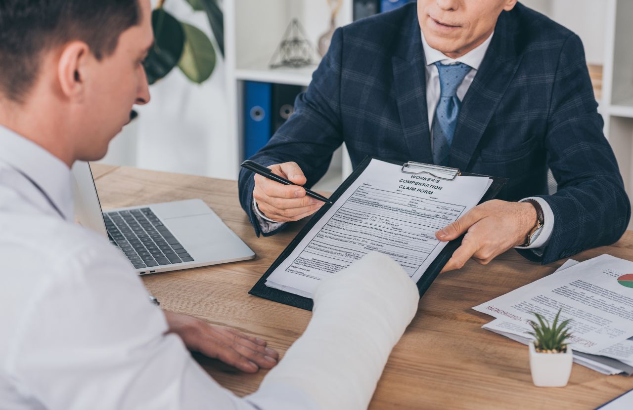 man in suit giving man with cast on right arm a workers compensation form