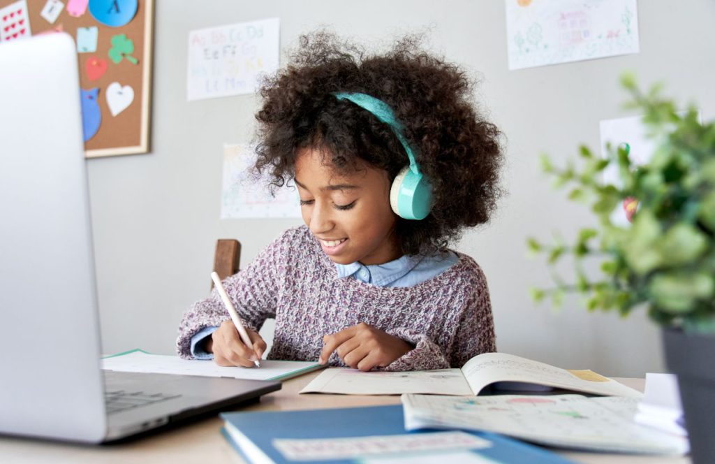 young girl wearing blue headphones doing school work